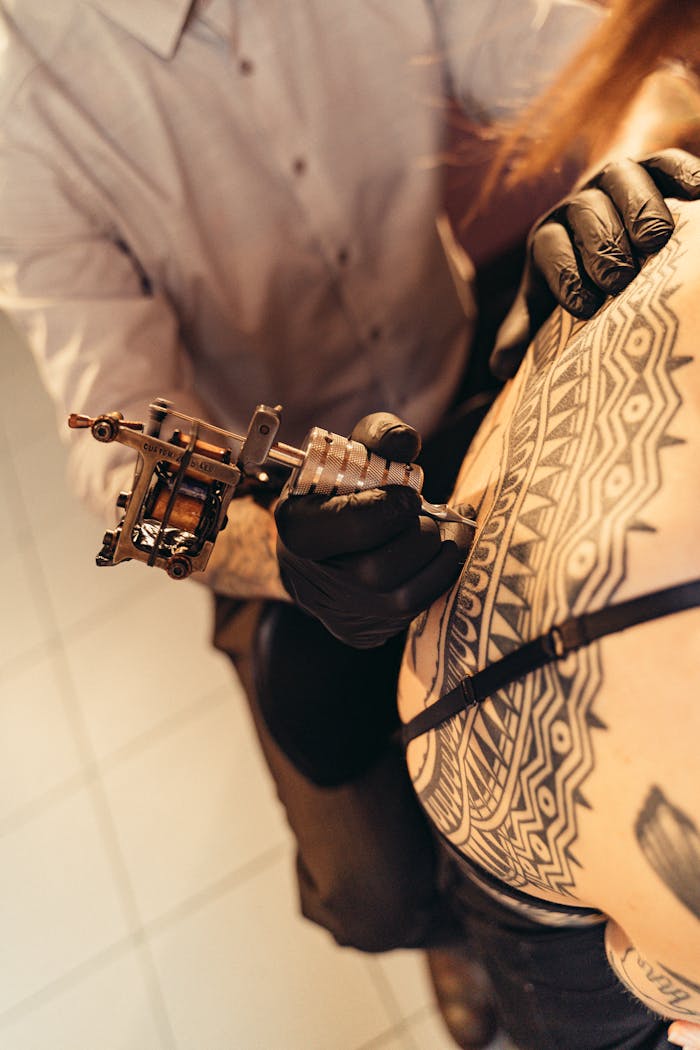 About Us Tattoo artist creating a detailed tribal tattoo on a client